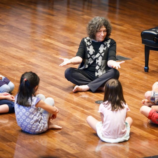 Young students in a Dalcroze class watch their teacher closely.